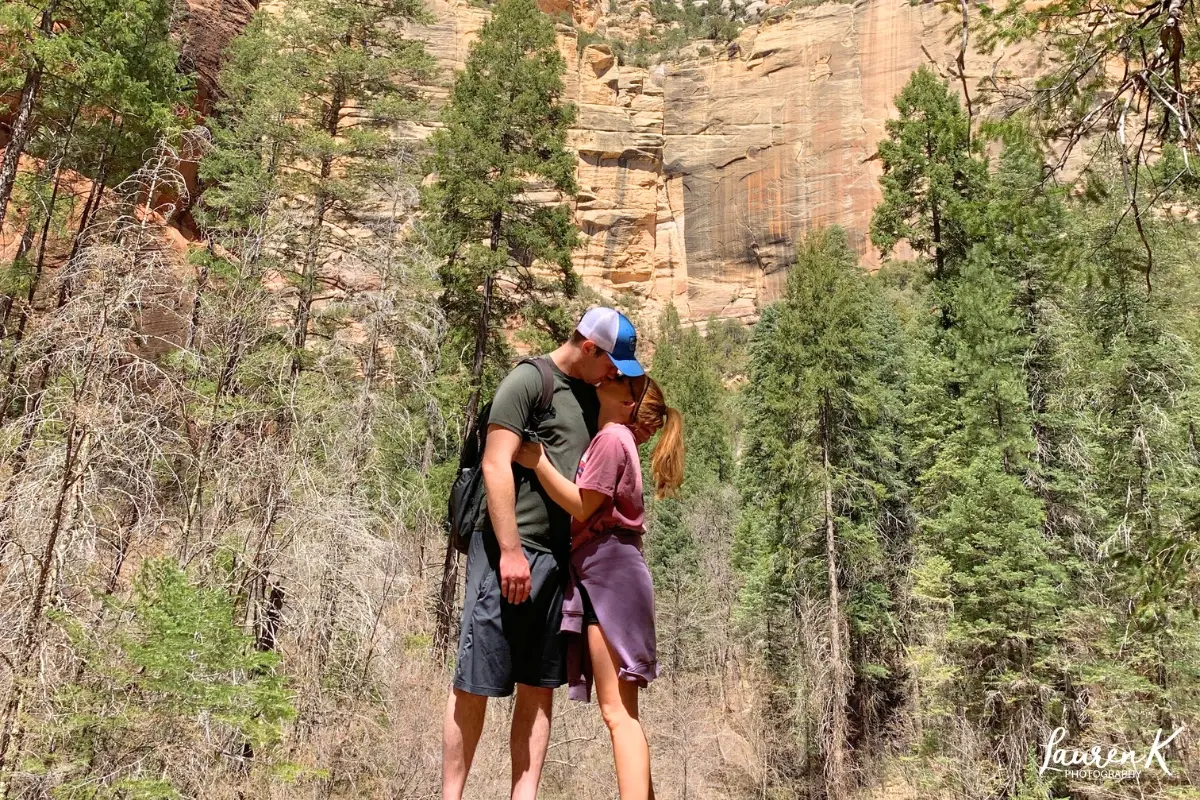 Cover image for the how to be a better partner blog, showing a couple kissing in a beautiful scenic woods